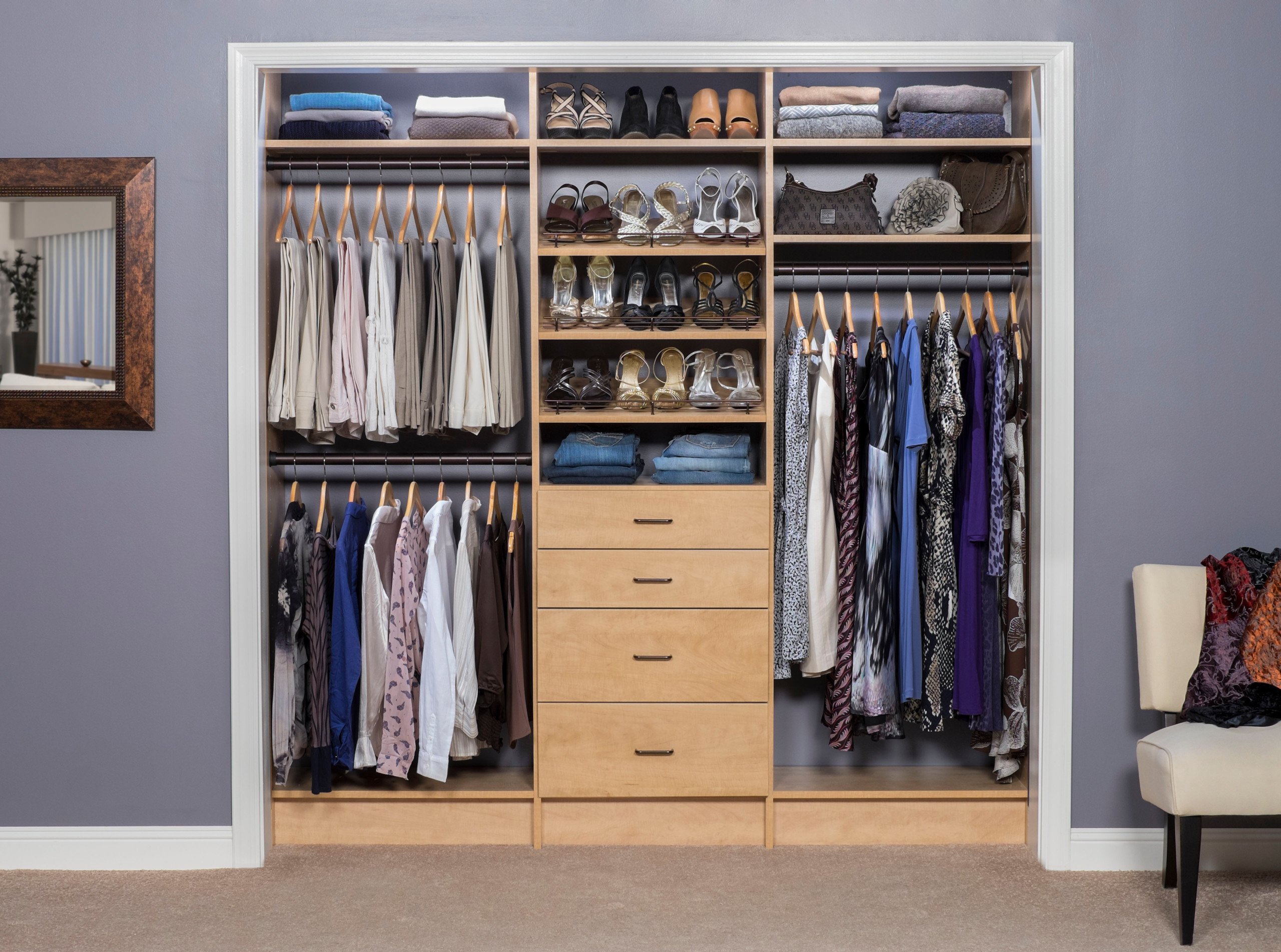 Built-in maple closet system with dual hanging rods, shoe shelves, drawers, and neatly organized clothing and accessories.
