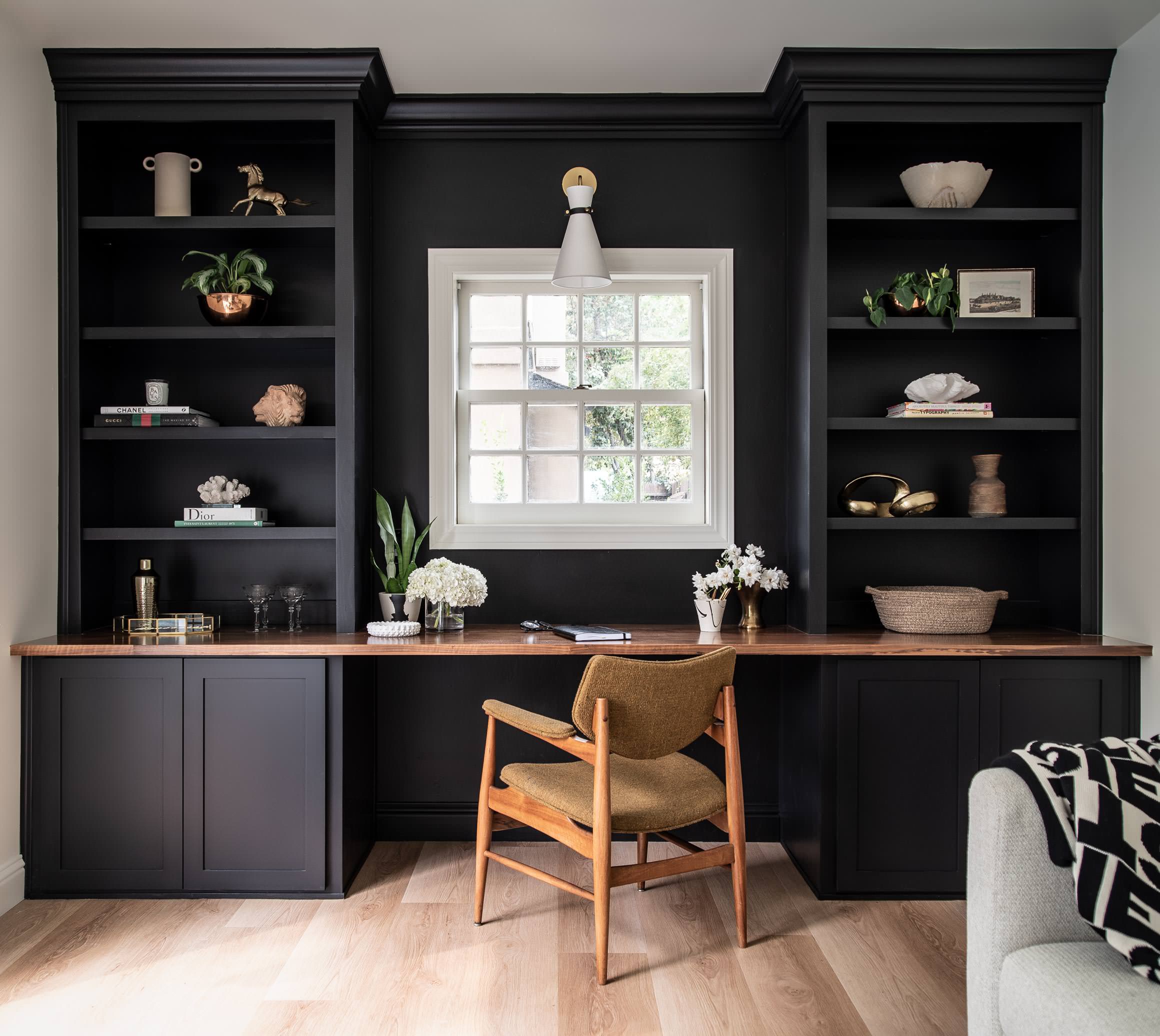 Dark charcoal built-in desk and shelves frame a window with a light wood surface.