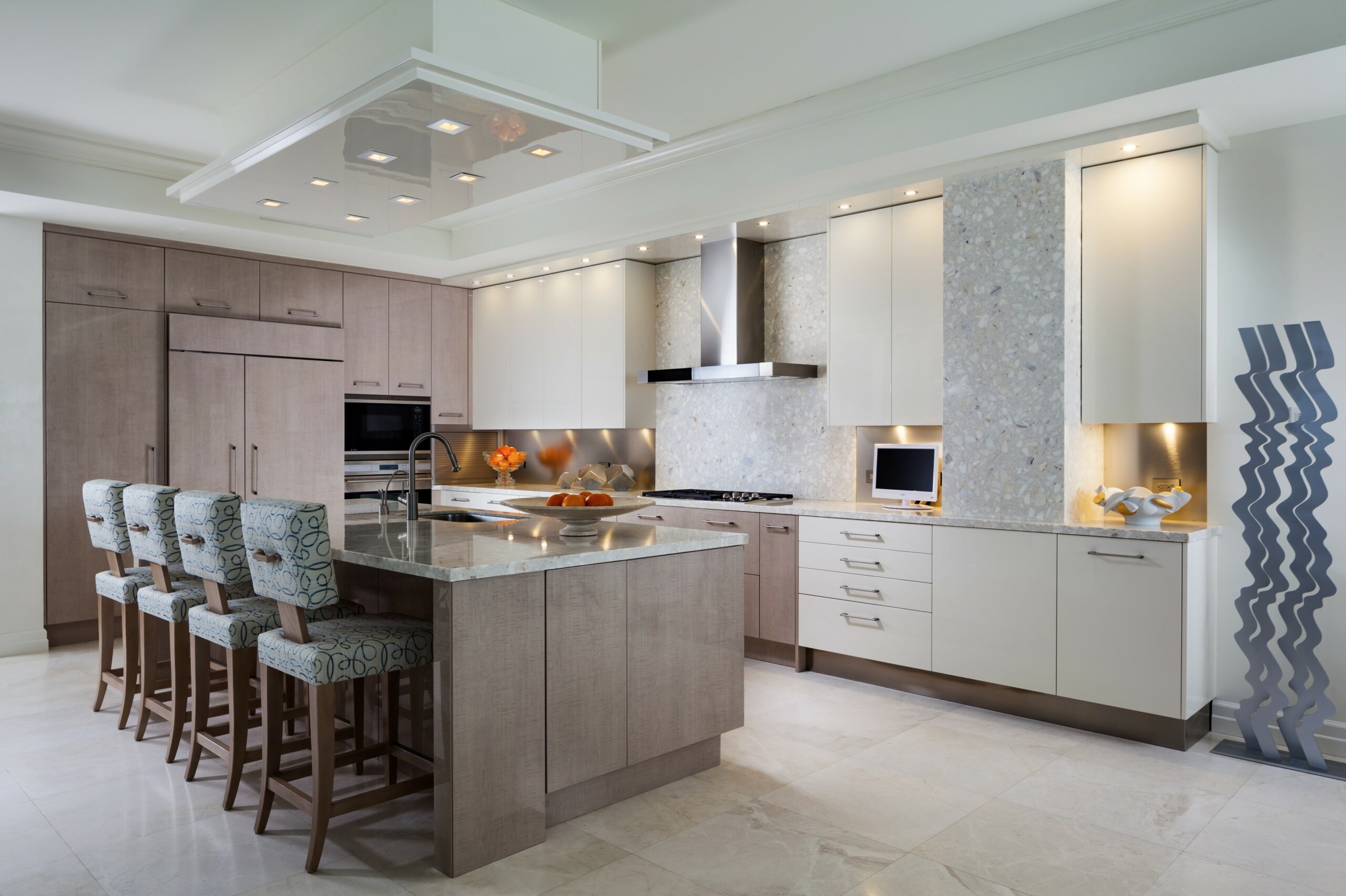 Contemporary kitchen with light wood and cream cabinetry, terrazzo backsplash, light marble floors, and patterned bar stools.
