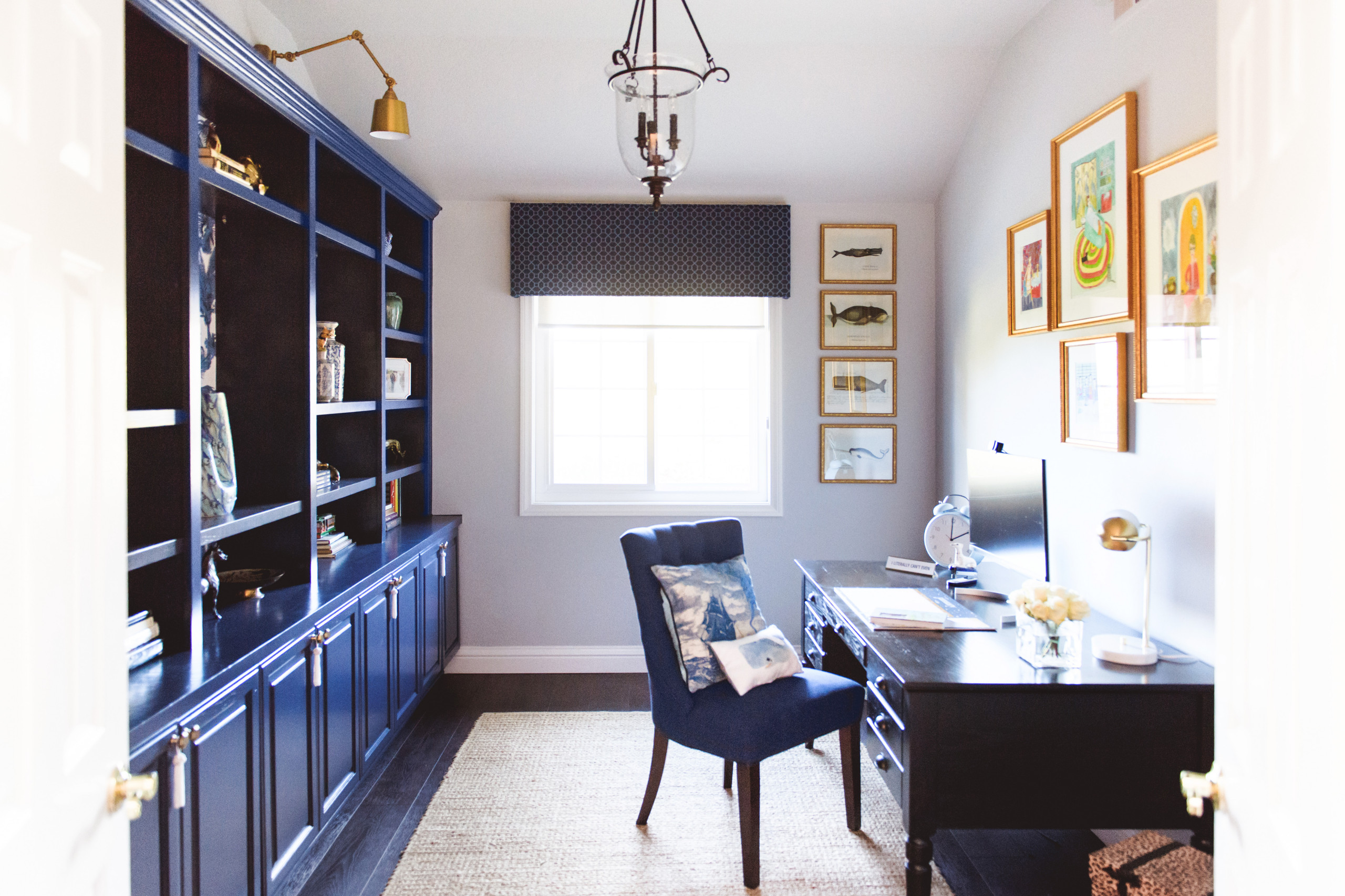 Navy blue built-in shelves and desk in a home office with a neutral rug and light gray walls.
