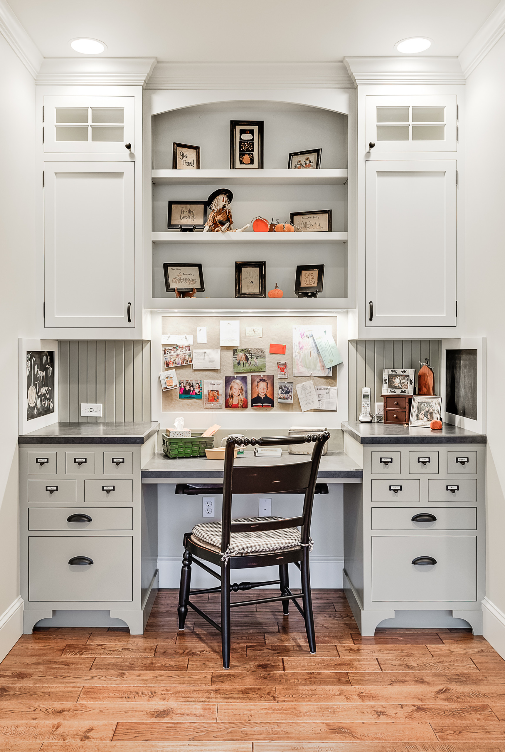 Traditional home office with built-in light gray desk, extensive cabinetry, open shelving, and dark wood chair.